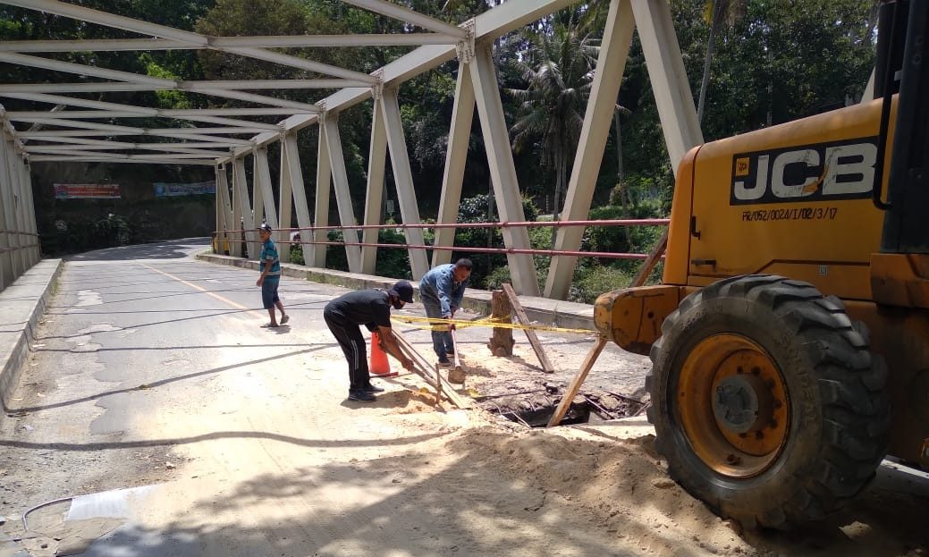 2 orang pekerja sedang memperbaiki bantalan jembatan yang rusak