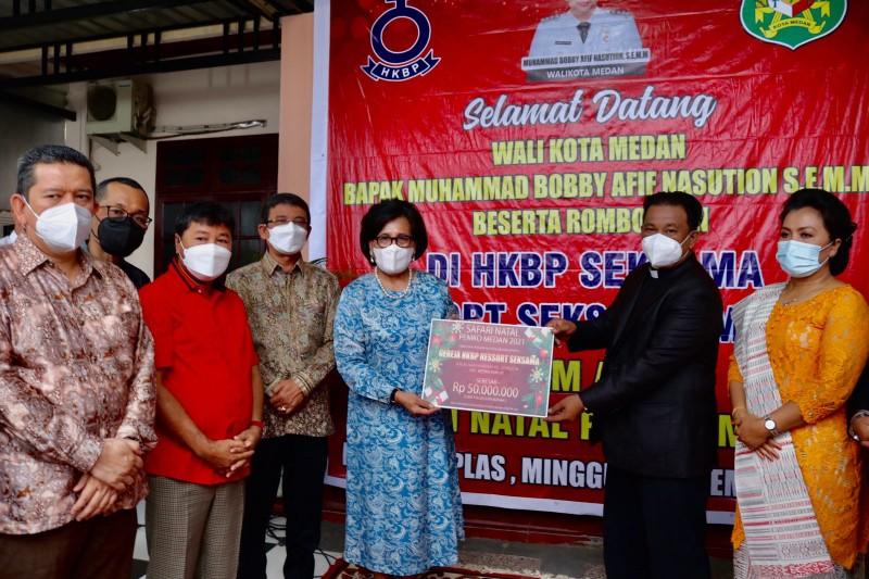 Wali Kota Medan, Bobby Nasution diwakili Kadisnaker, Hanna Lore Simanjuntak menyerahkan bantuan sebesar Rp 50 juta dan paket Natal untuk Gereja HKBP Seksama, Kecamatan Medan Amplas, Minggu (12/12/2021).